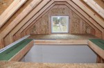Light through the south-facing gable window illuminates the loft and spills through the access hatch to the shed below.